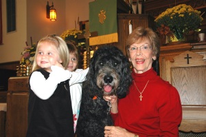 Children rush up to pet Reggie before the service when Judy Brown and her therapy dog come for the children’s moment.