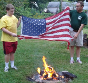 Mark Gray and Anthony Gray demonstrate the ceremonial burning of a tattered American flag.